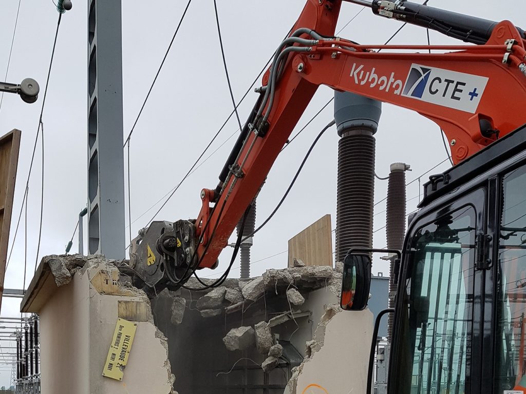 Démolition du toit en béton armé d'un bâtiment de relayage (BR) avec pince cisaille.